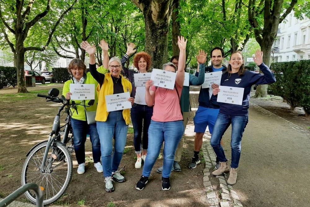 Eine Gruppe von Mitarbeitenden der Stiftung hält ihre Registrierungen hoch und winken vor dem Start ihres gemeinsamen Laufs.